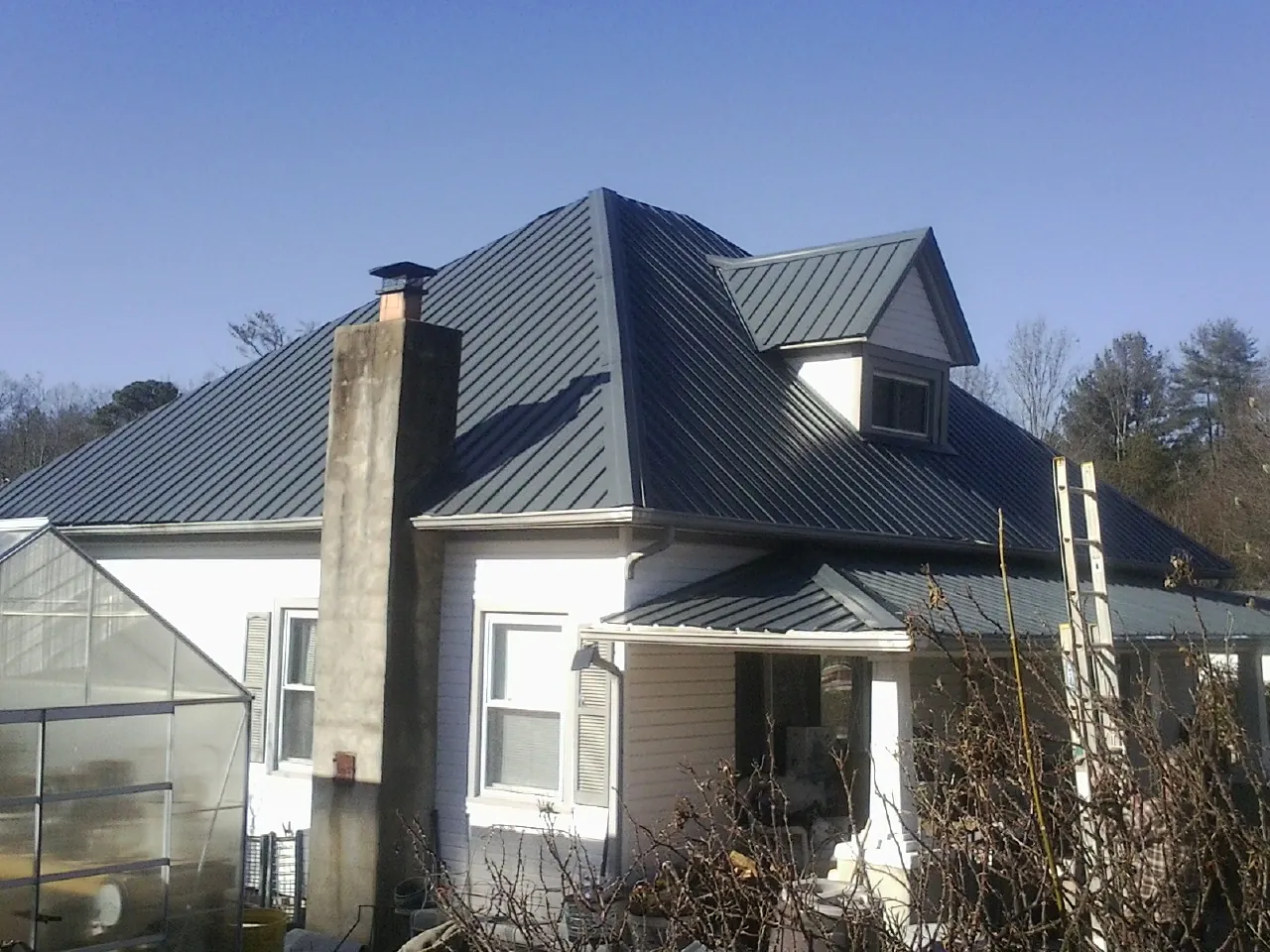 Dark blue standing seam metal roof on a white farmhouse with dormer — Slate & Tile Roof Repair by Roofing Brothers in Guys Mills