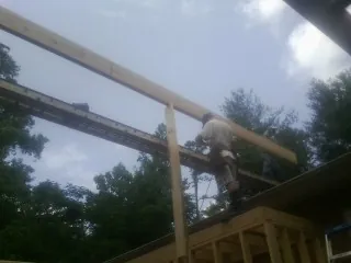 Carpenter setting a ridge beam over a new addition frame — Ice Dam Removal by Roofing Brothers in Guys Mills