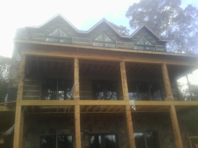 Dormers and porch framing on a large log home under construction — Roof Coating work by our crew in Guys Mills