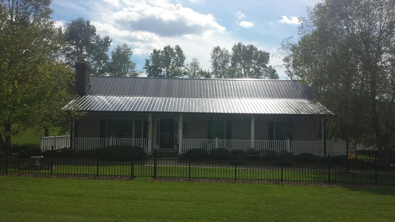 Gray metal roof on a brick ranch with a full width front porch — Gutter Guard Installation work by our crew in Guys Mills