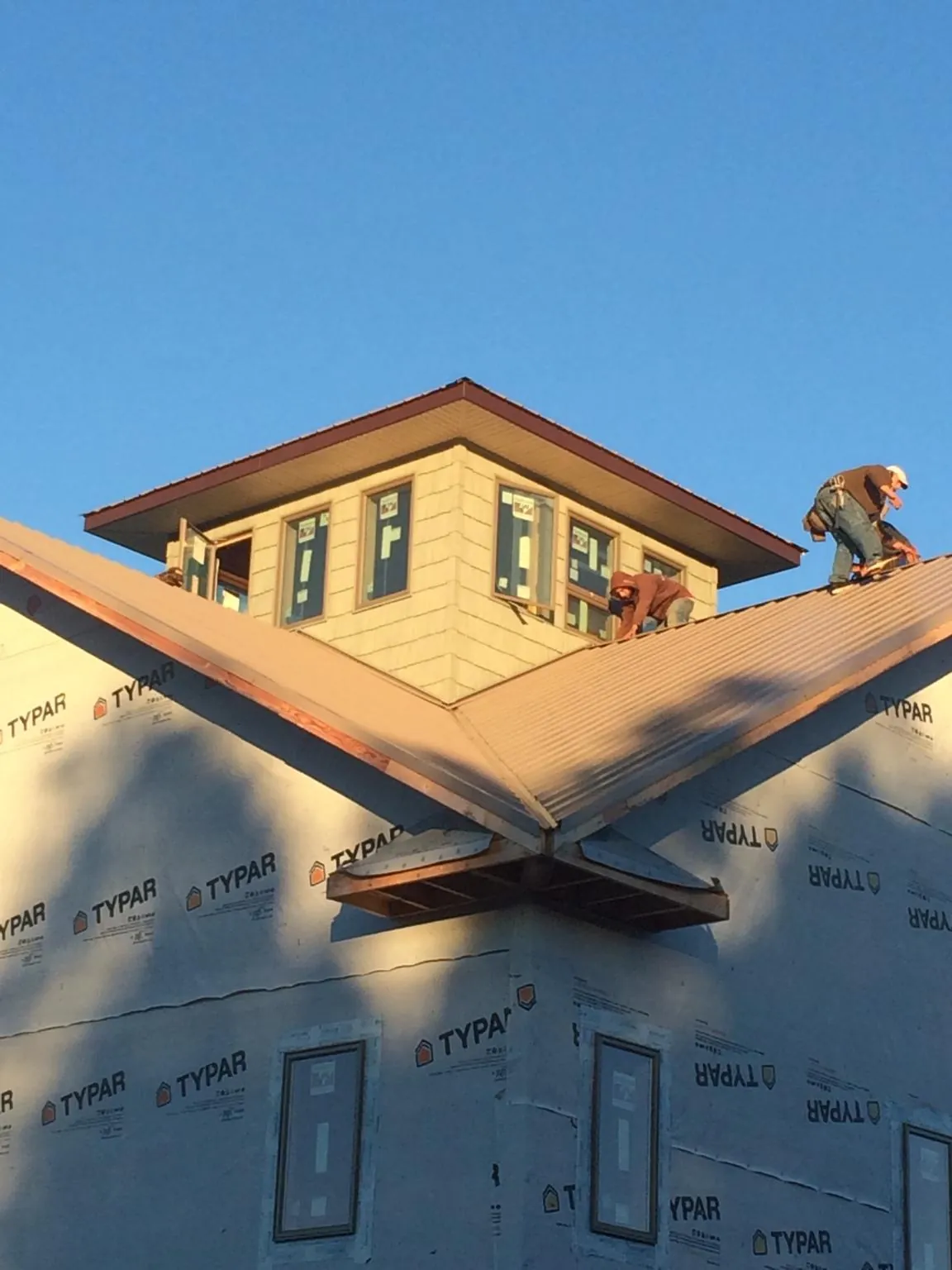 Roofers working around a rooftop cupola on a new metal roof at sunset — Roof Waterproofing in Guys Mills by Roofing Brothers